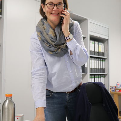 Die Leiterin der Musikschule Frau Türich stehend an ihrem Schreibtisch mit dem Telefonhöhrer in der Hand.