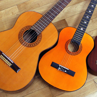 Zwei Konzertgitarren liegen auf einem Holzfußboden